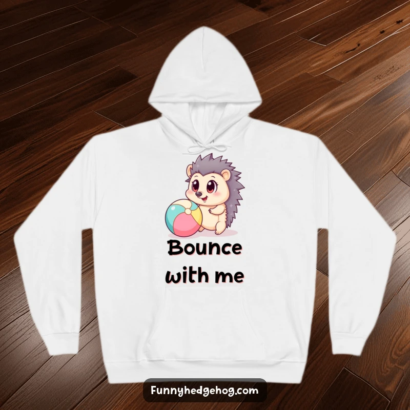 Funny hoodie featuring a delightful hedgehog with oversized eyes playfully bouncing a beach ball, exuding carefree happiness.