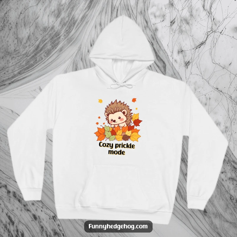 Funny Hedgehog Hoodie: A spiky kawaii hedgehog peeking adorably from a heap of vibrant autumn leaves, perfect for cozy, humorous wear.