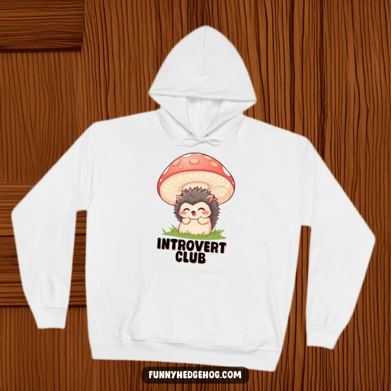 Funny hoodie showing a bashful hedgehog peeking from behind a huge, happy mushroom, designed for comfort and a good laugh.